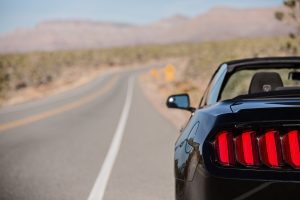 Car drives on an empty Texas country highway with mountains in the background.
