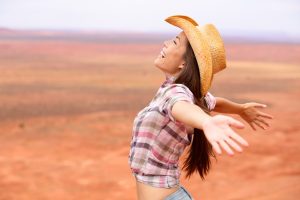 Beautiful cowgirl spreading her arms wide in the Vermont countryside.